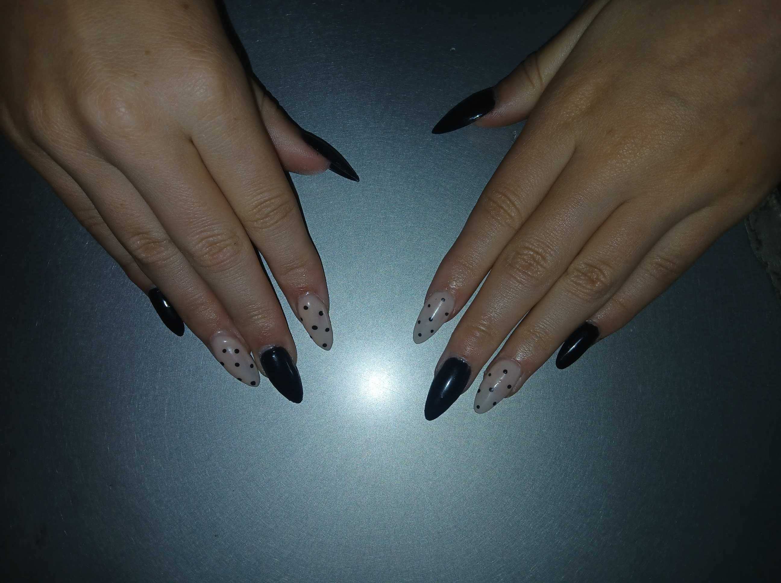 Black and nude polka dot nails worn on hands